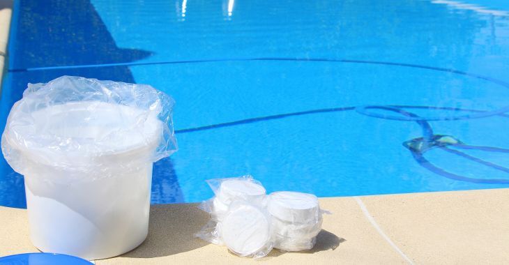 chlorine and sanitization tablets on the edge of a swimming pool with clear water