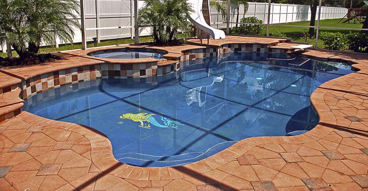 A backyard swimming pool with the resurfaces travertine deck