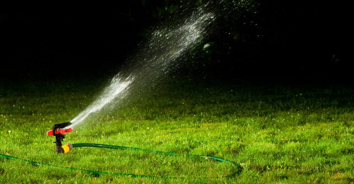 Lawn sprinkler watering grass at night